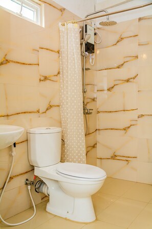 A bathroom with a toilet, a sink, and a shower with a curtain. - ShiCo Transit Hotel (Seeduwa - Katunayake)
