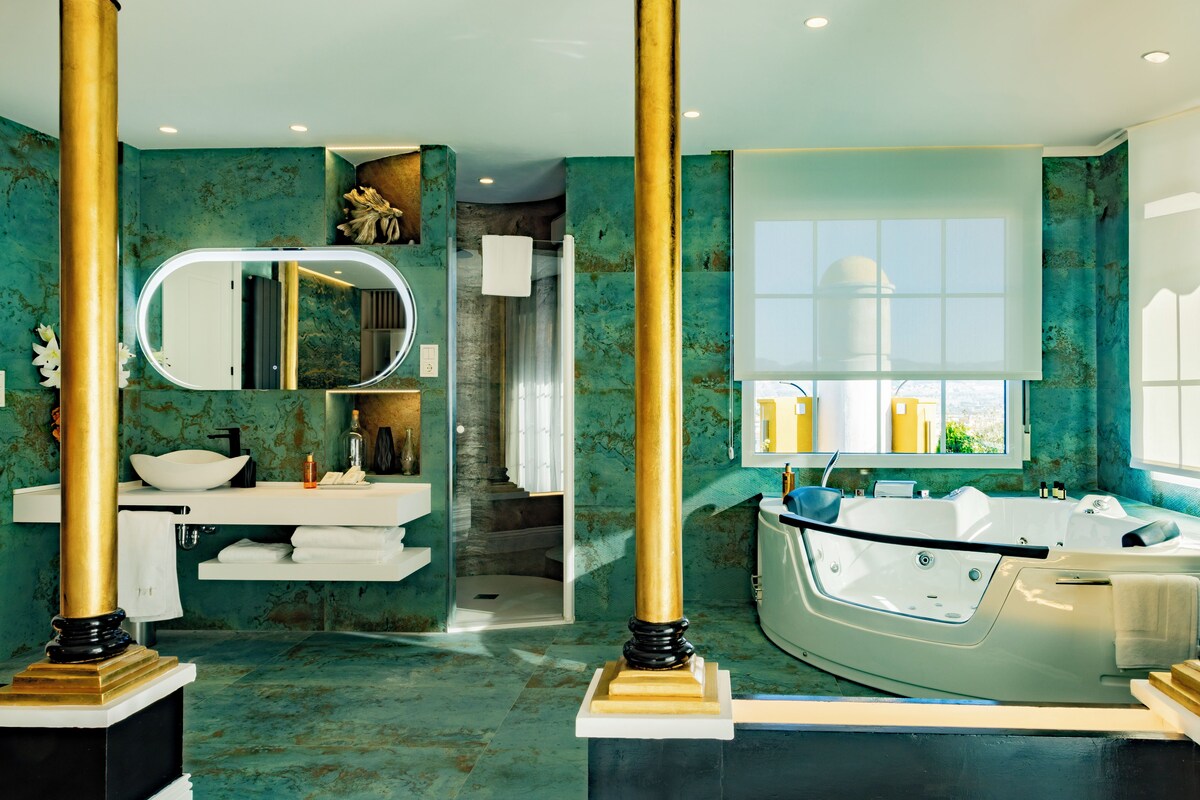 Une salle de bain luxueuse avec un sol en marbre, une baignoire sur pieds, un grand miroir et un meuble-lavabo avec un vasque.
