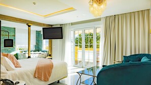 Quarto de hotel moderno com cama, sofá, televisão e varanda com vista.