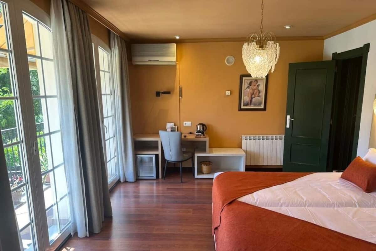 Un dormitorio con cama, escritorio, silla y ventana con cortinas.