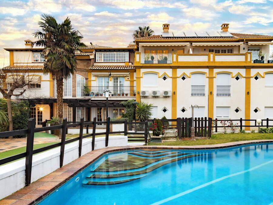 Edificio de dos plantas con piscina, patio cercado y jardín bien cuidado.