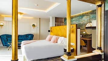 A modern hotel room with a large bed, a desk, and a blue sofa.