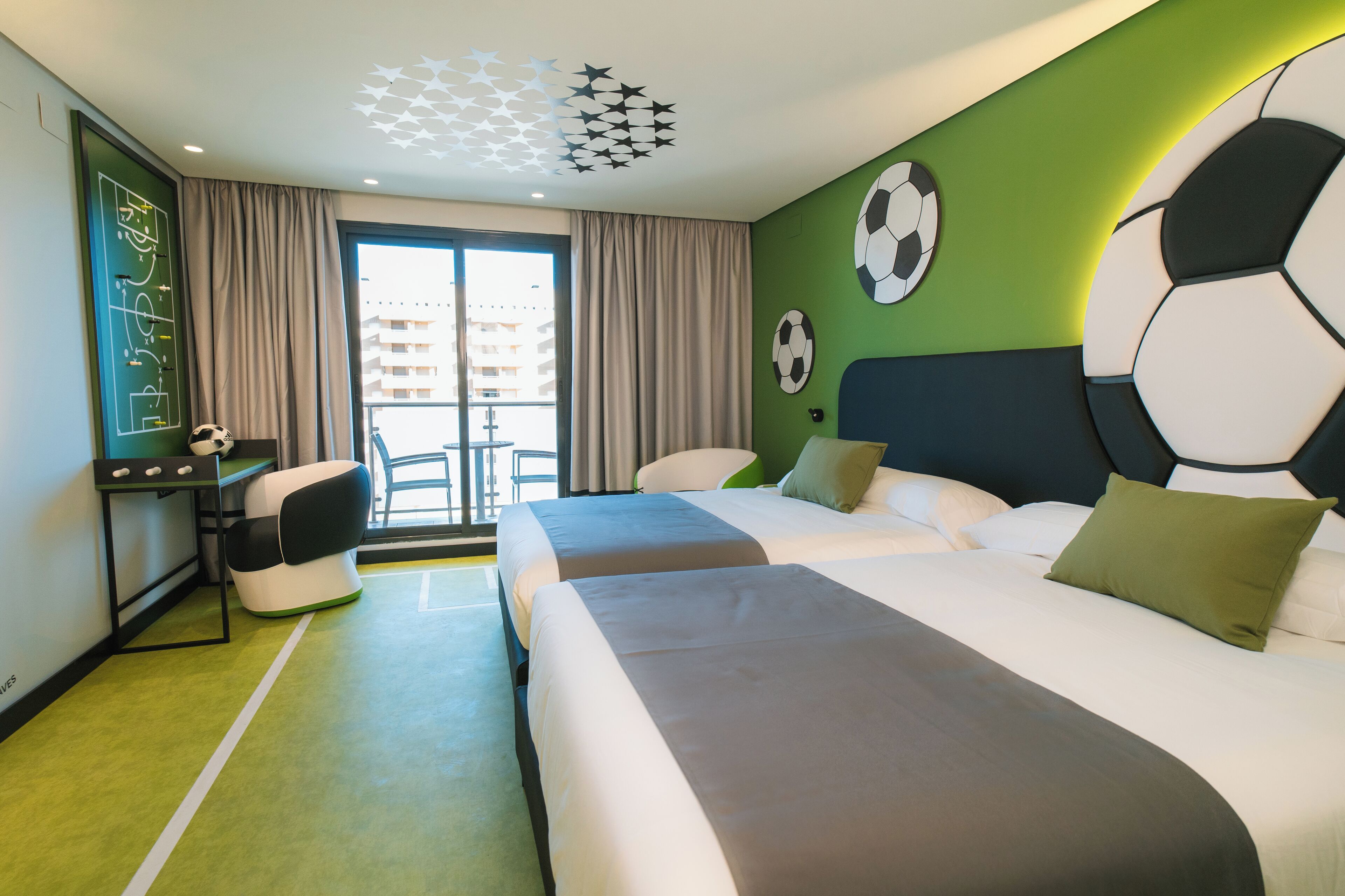 Habitación de hotel con dos camas, un escritorio y vistas a la ciudad.