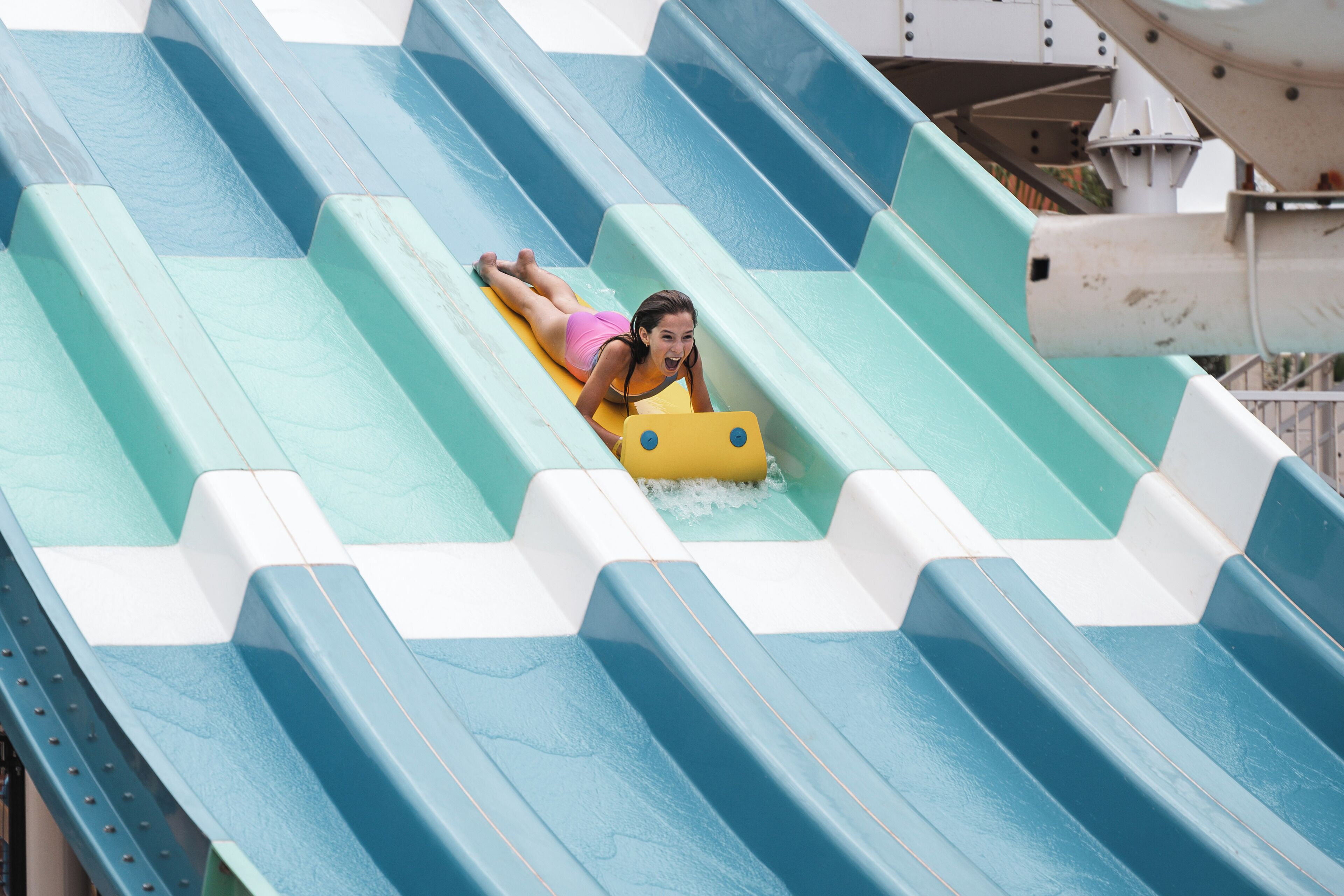 Une personne descend une toboggan aquatique sur un radeau jaune.
