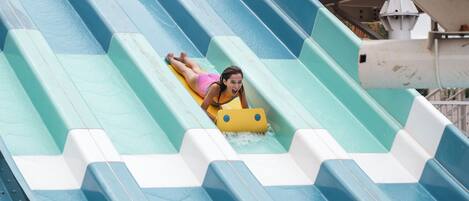 A person sliding down a water slide with a yellow raft.