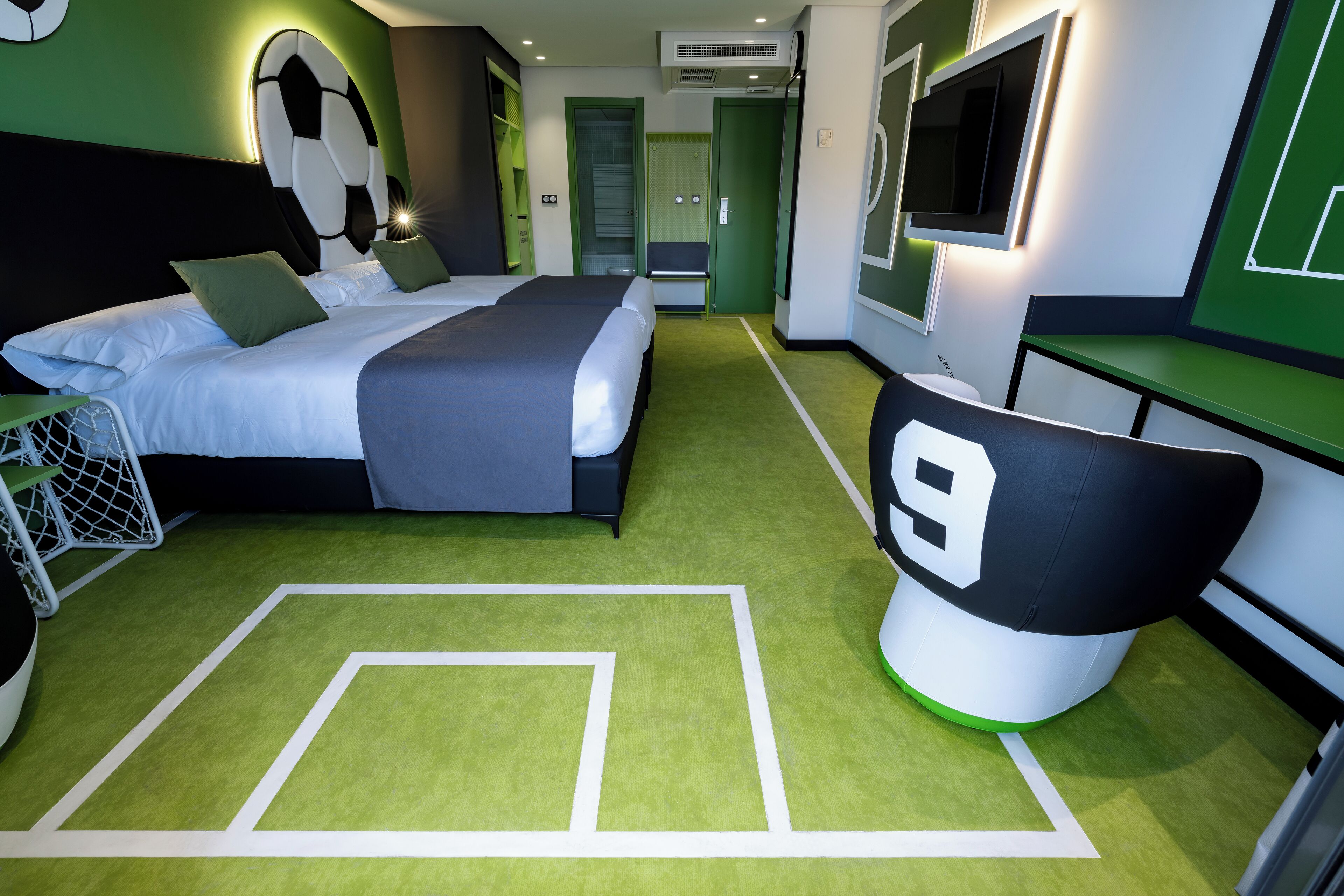 A hotel room with a large bed, a desk, a chair, and a TV.