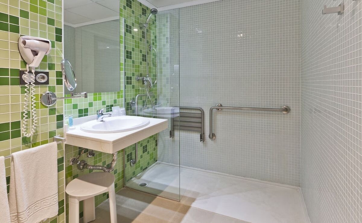 Une salle de bain équipée d’un lavabo, d’un miroir et d’un sèche-cheveux fixé au mur.