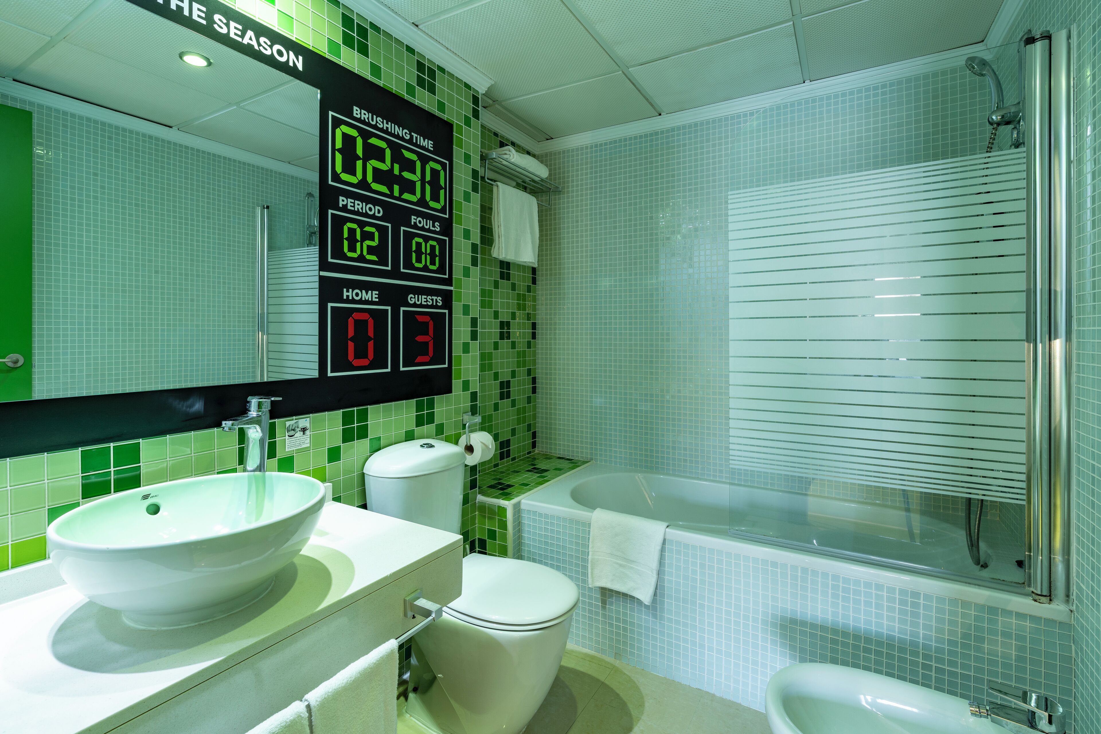 Un baño con un reloj digital, un lavabo, un inodoro y una bañera.