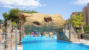 Relax by the pool surrounded by lush greenery and amenities like a slide, play area, and climbing net.
