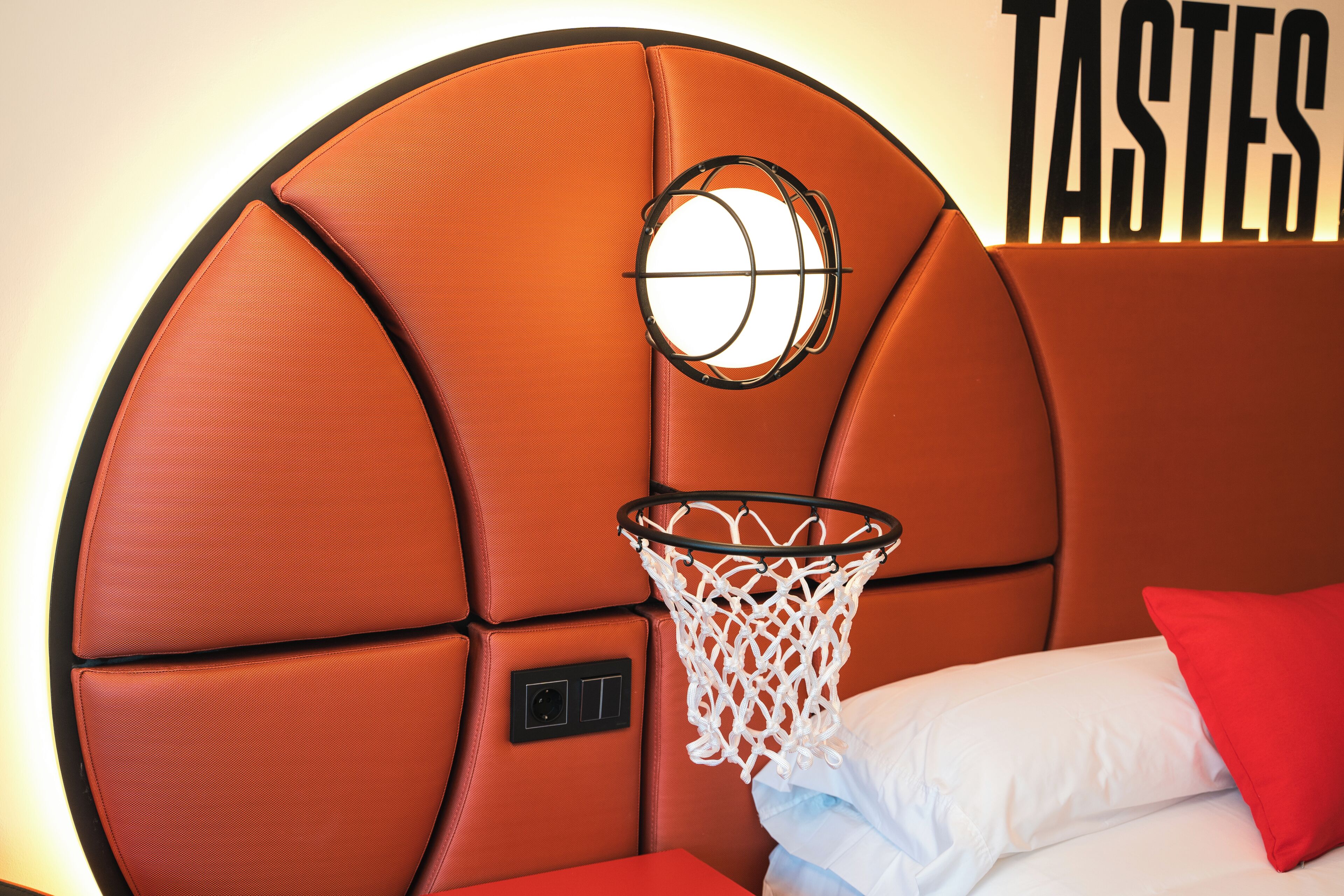 Un panier de basket intégré à une tête de lit, avec un lit et des oreillers à proximité.