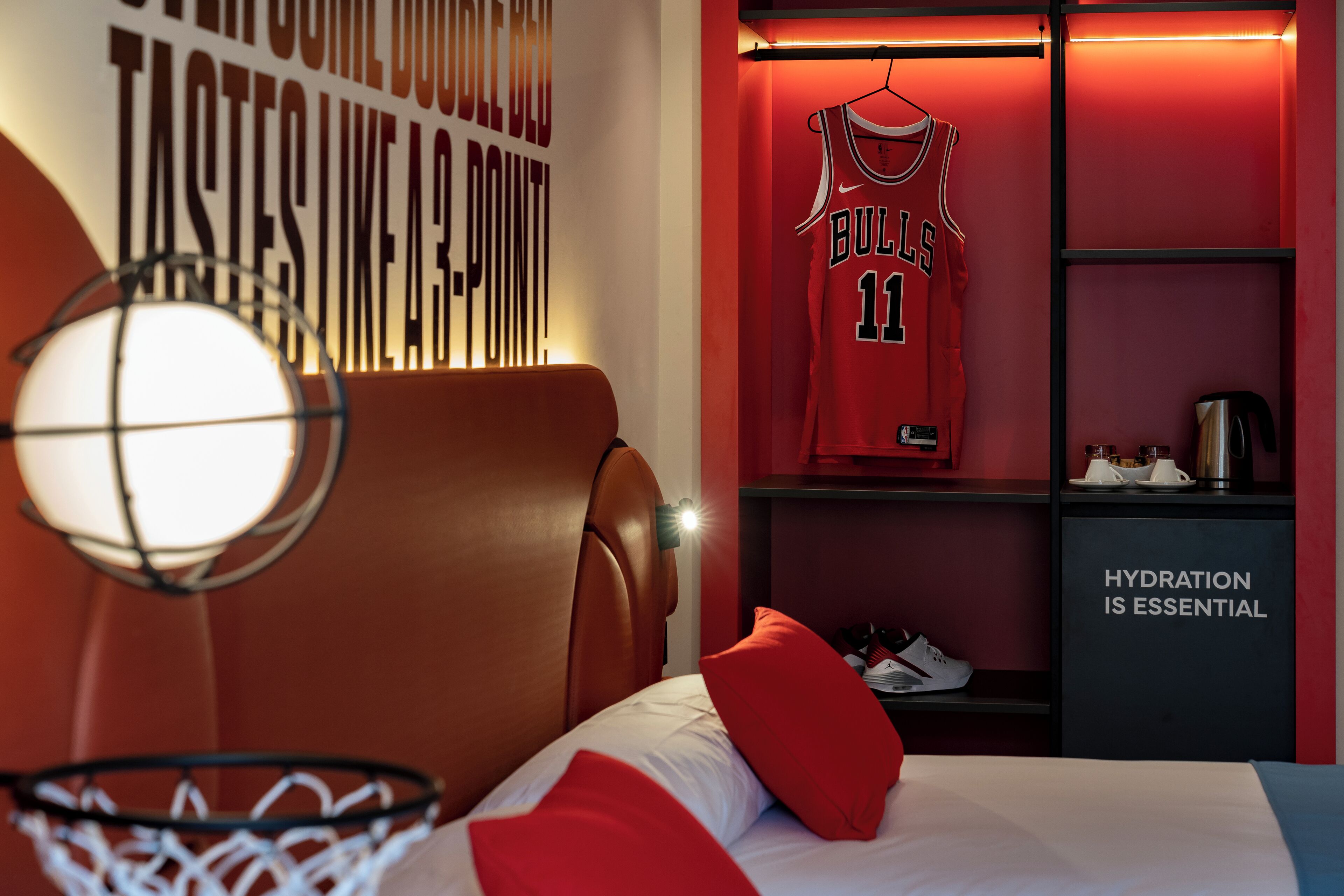 Una habitación de hotel con temática de baloncesto, que incluye una camiseta en la pared, una estación de hidratación y un aro de baloncesto.