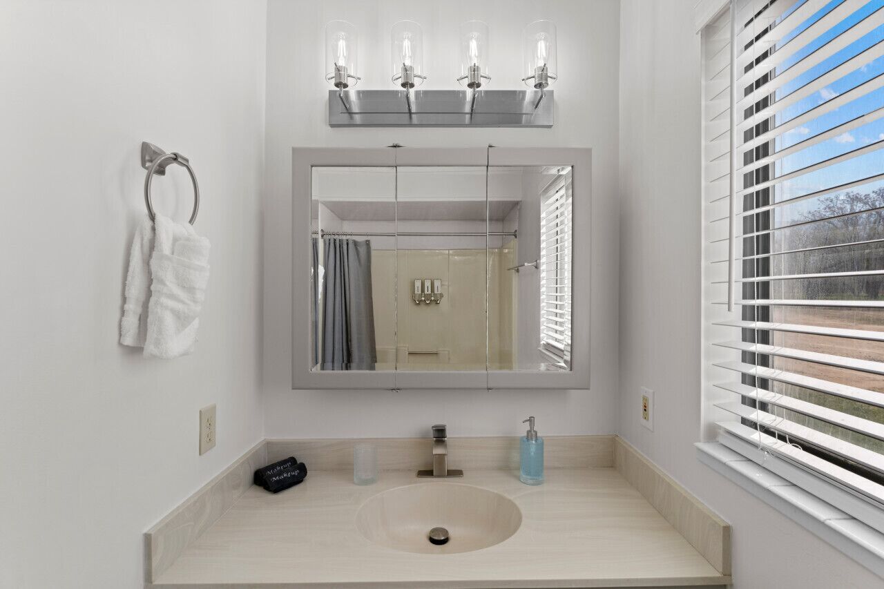 A modern bathroom with a large mirror, a sink, and a towel rack.