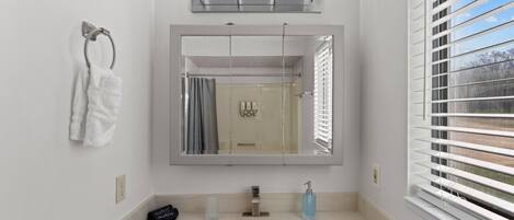 A modern bathroom with a large mirror, a sink, and a towel rack.