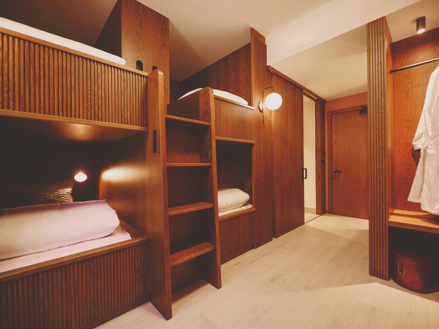 Una habitación con literas de madera, un vestidor y una bata colgada.