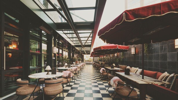 A spacious indoor dining area with checkered flooring, round tables, and cushioned seating. - Mollie's Manchester (Manchester)