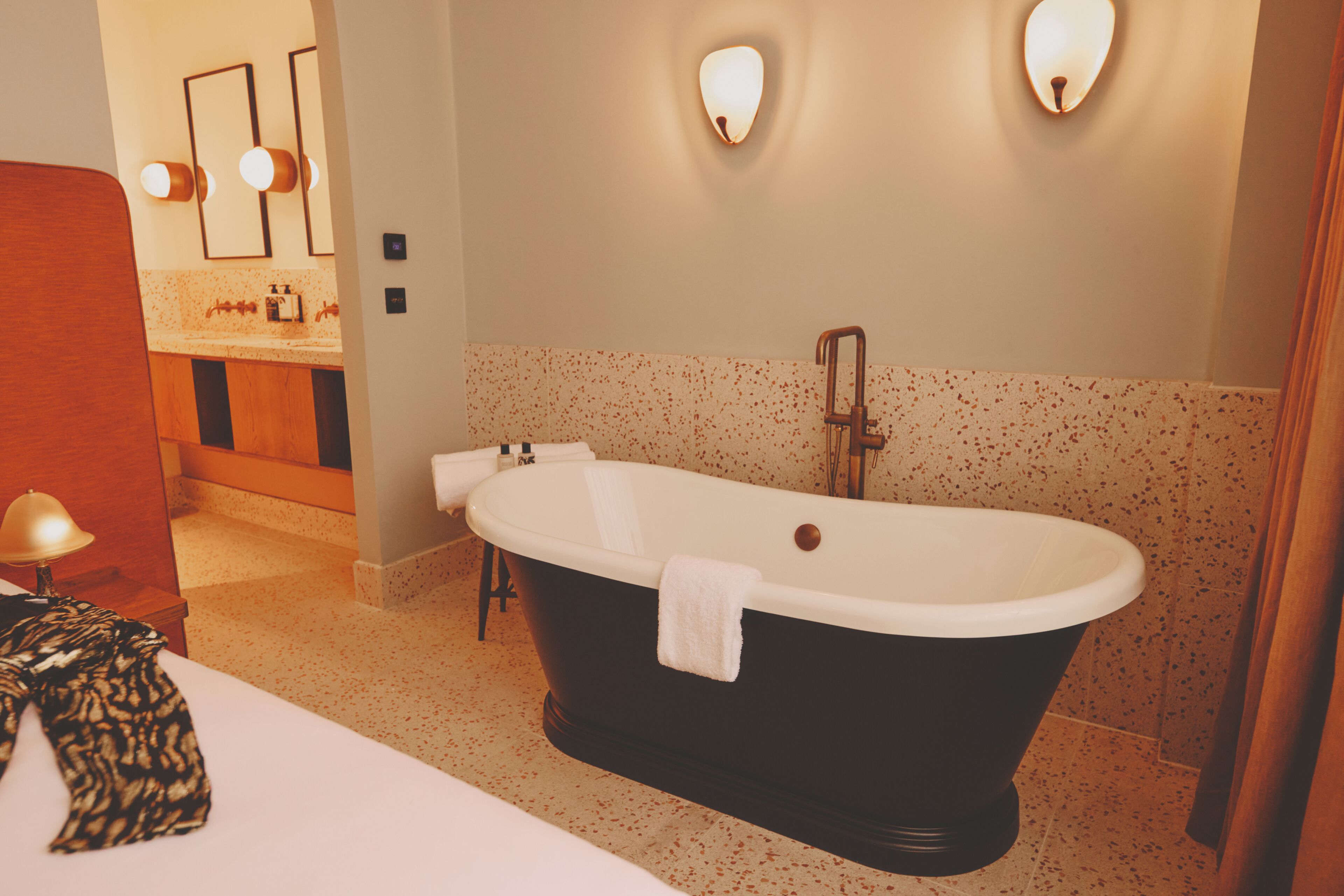 A bathroom with a freestanding bathtub, a vanity with a mirror, and a towel on the floor.