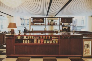 Una zona de bar con suelo a cuadros, mostrador de madera y estantes con diversos objetos.