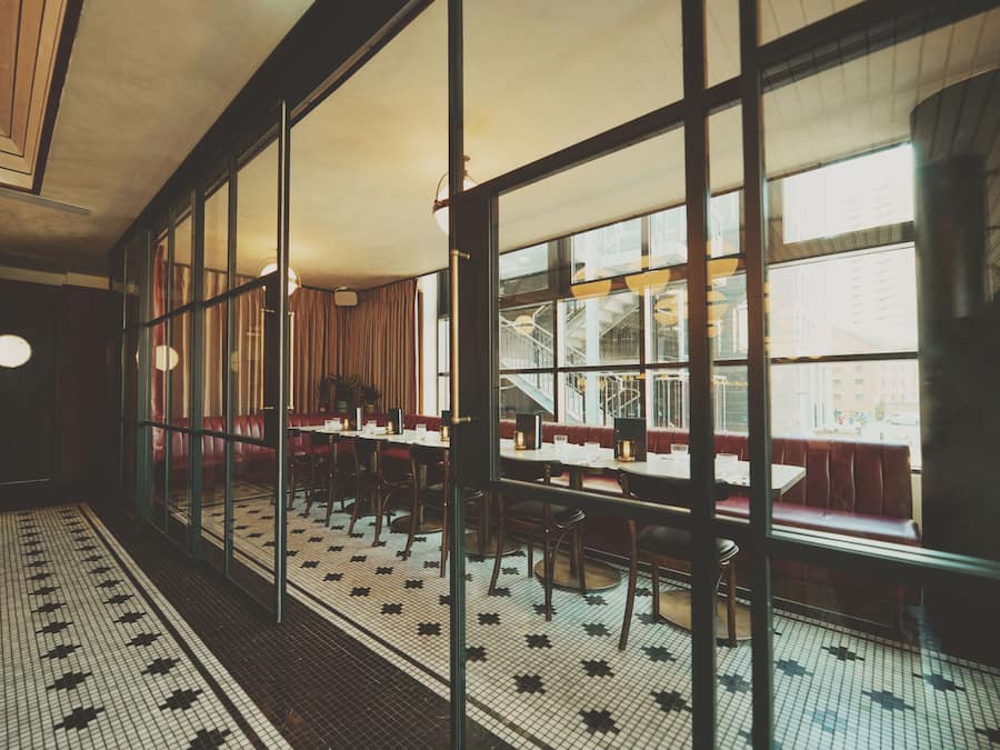 A restaurant with a tiled floor, glass partitions, and red booths.