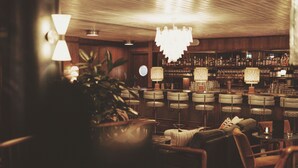 A bar area with multiple seating arrangements, a chandelier, and a well-stocked bar. - Mollie's Manchester (Manchester)