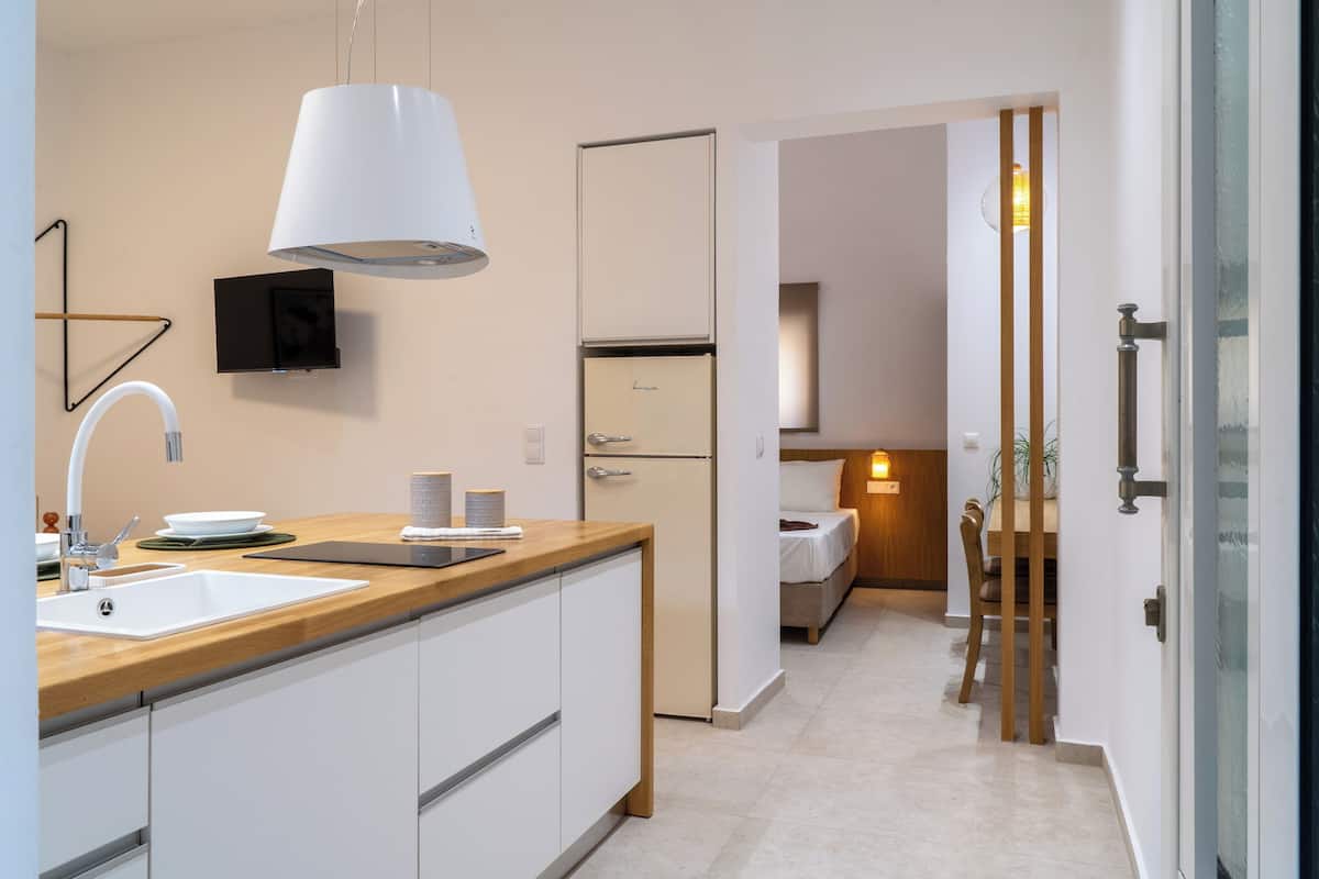 A modern kitchen with a wooden countertop, white cabinets, a built-in sink, and a white refrigerator.
