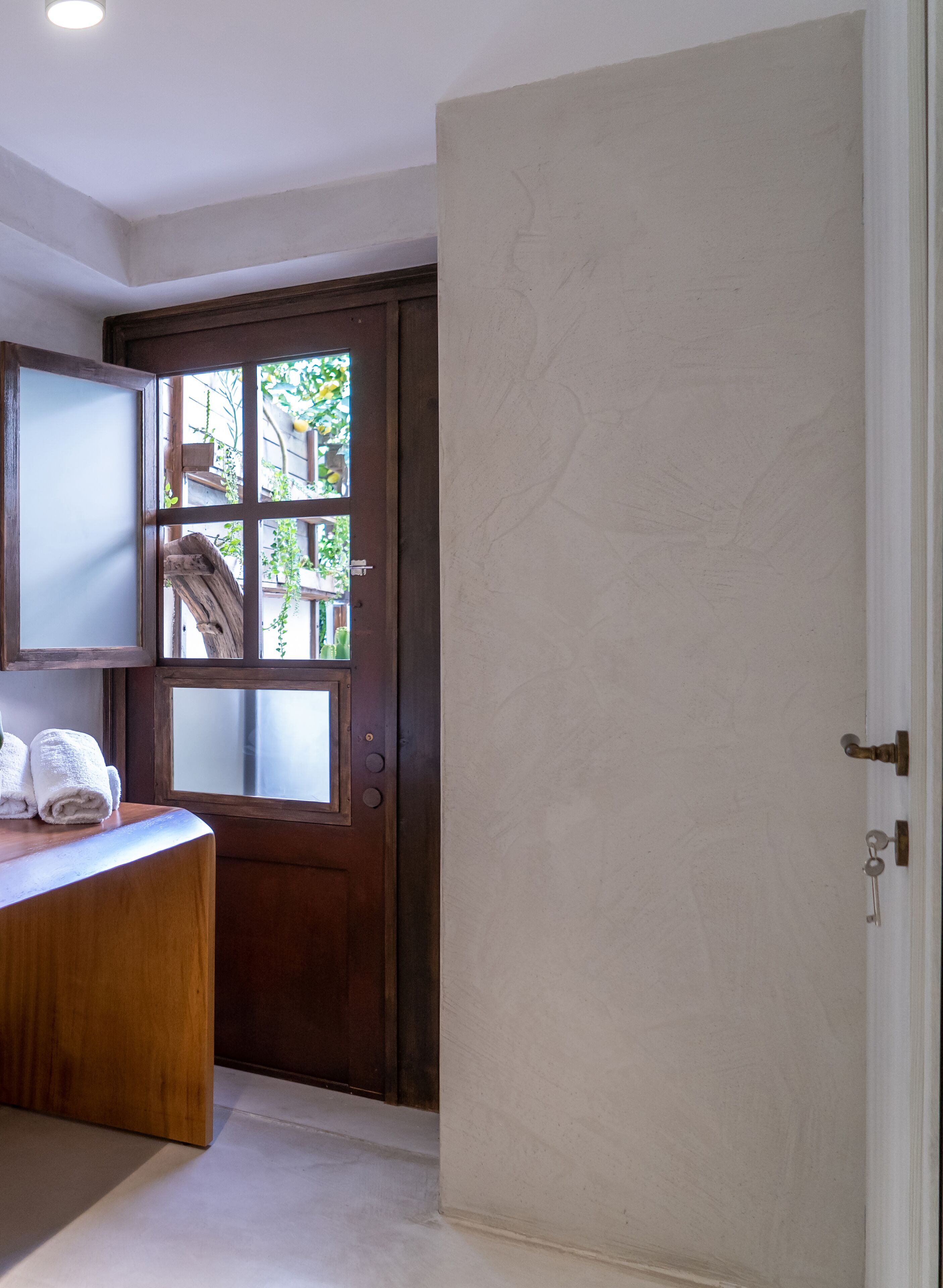 A bathroom with a wooden vanity, a towel rack, and a door with frosted glass panels.