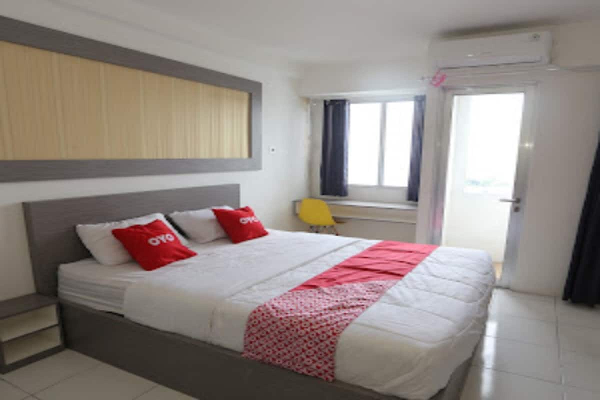 A hotel room with a bed, a desk, and a window.
