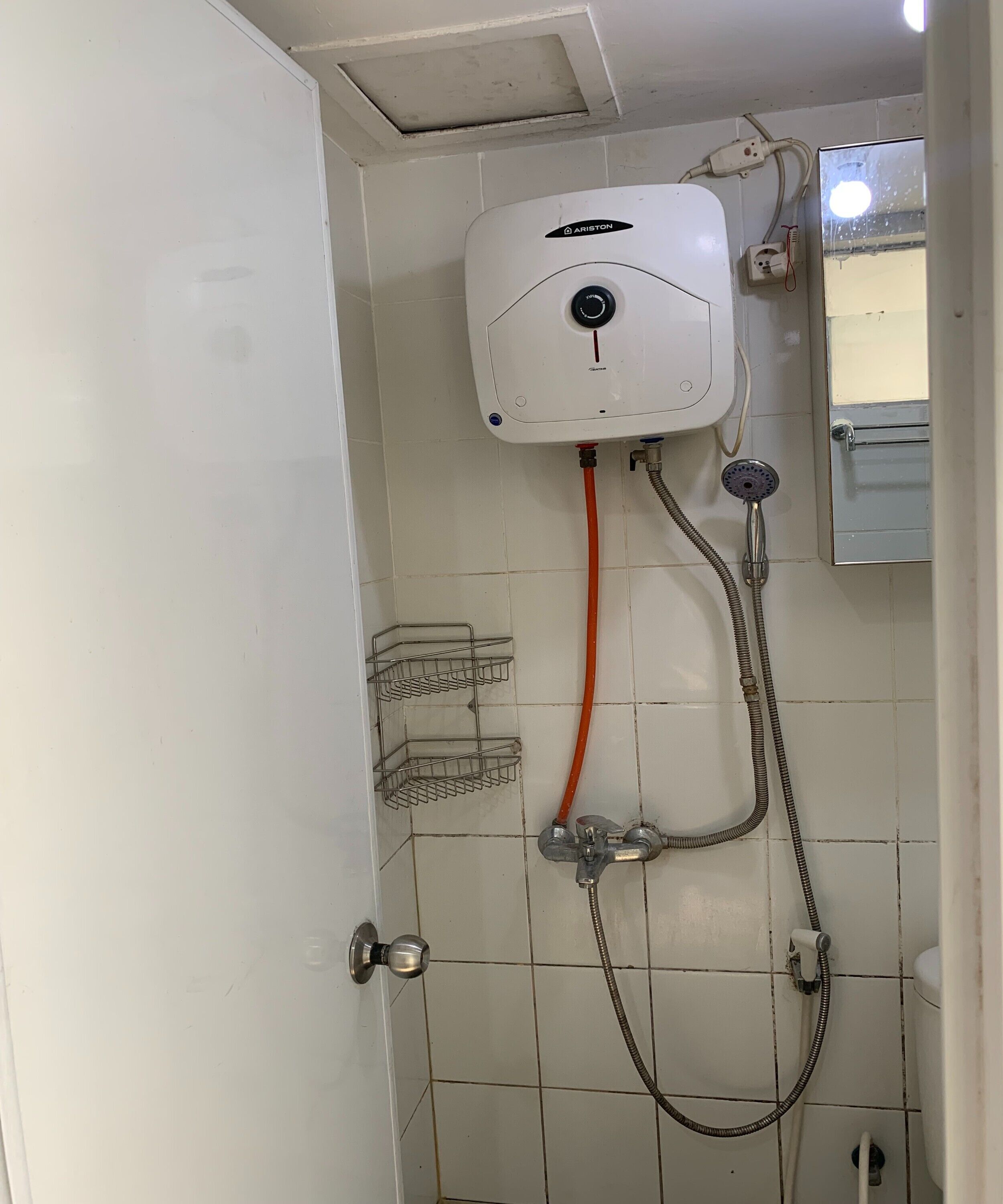 Ein Badezimmer mit einer weißen Duschkabine, einer Handbrause und einer fest installierten Armatur.