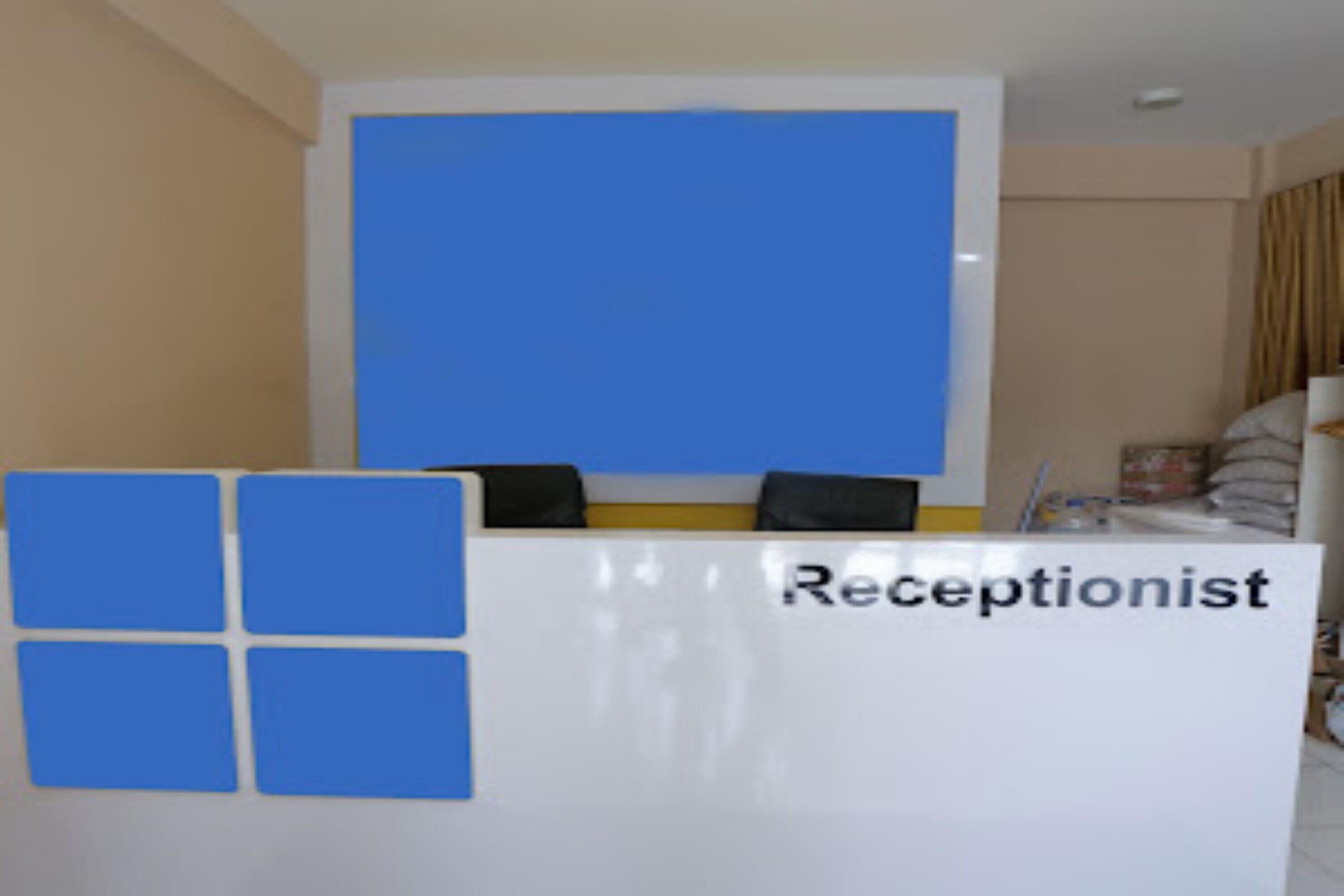 Un comptoir d’accueil avec une pancarte indiquant « Réception » et un logo bleu.