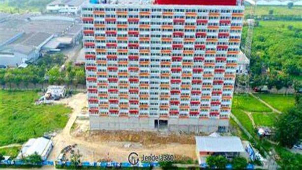 Un edificio alto con una serie de balcones, rodeado de vegetación y una obra en construcción.