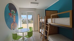 A room with bunk beds, a round table with chairs, and a mural on the wall.