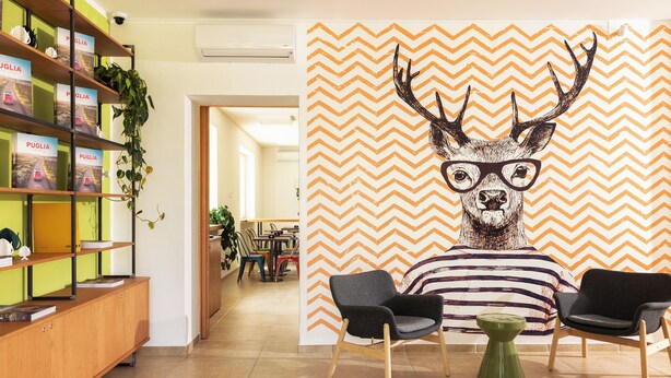 A modern interior with a bookshelf, a large wall mural, and two chairs.
