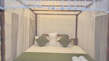 A bed with a canopy, pillows, and rolled towels.