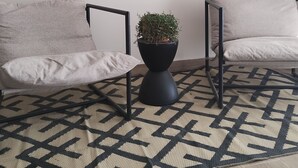 Una sala de estar moderna con un cuadro de un paisaje urbano, dos sofás, una lámpara de pie negra y una alfombra estampada.