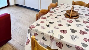 A compact kitchen with white cabinets, a black stove, and a dining table with a heart-patterned tablecloth. - AmareSardegna 3 (Muravera - Costa Rei)
