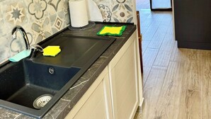 A kitchen with a black sink, a microwave, and patterned tiles. - AmareSardegna 3 (Muravera - Costa Rei)