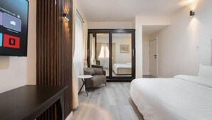 A hotel room with a bed, a small table, a chair, and a TV mounted on the wall displaying a weather forecast and Netflix logo. - vacationhomesng (Lagos)