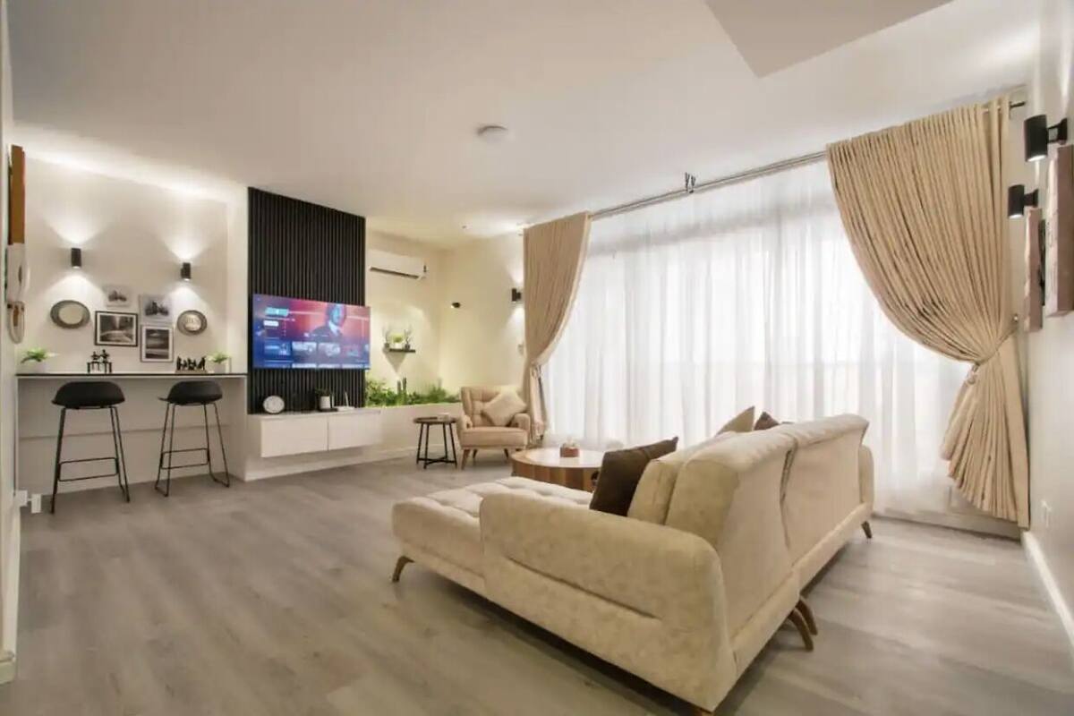 Un salon moderne avec un canapé, un téléviseur et un coin bar équipé de tabourets.