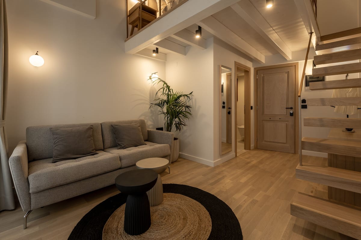A modern living room with a sofa, a coffee table, and a staircase.