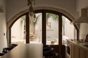 Una cocina moderna con una isla grande, armarios de madera y vistas a una piscina y zona de estar exterior.
