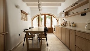Una cocina moderna con armarios de madera, una mesa de comedor con sillas y vistas a un patio a través de un arco.