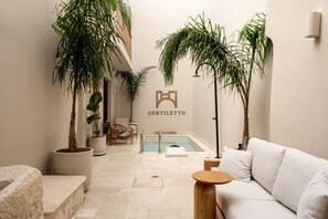 A spa area with a pool, seating, and potted plants.