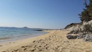 Enjoy a serene beach experience with a clear view of the sea and a rugged cliff line.