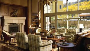 A spacious living room with a fireplace, large windows, and a view of a forested area. - Ritz-Carlton Residence Club Vail, CO Luxury 3 Bedroom 
Condo Resort- Sleeps 8 (Vail)