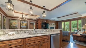 A spacious kitchen with wooden cabinets, a granite countertop, and a built-in dishwasher. There are hanging lantern-style lights and a large window providing a view of the outdoors. - Ritz-Carlton Residence Club Vail, CO Luxury 3 Bedroom 
Condo Resort- Sleeps 8 (Vail)