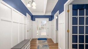 A hallway with white paneling, a blue accent wall, a wooden floor, and a patterned rug. - Five Bedroom Waterfront Home with Lots of Space (Ocean City)