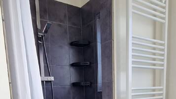 A bathroom with a shower area, a white towel rack, and a tiled floor.