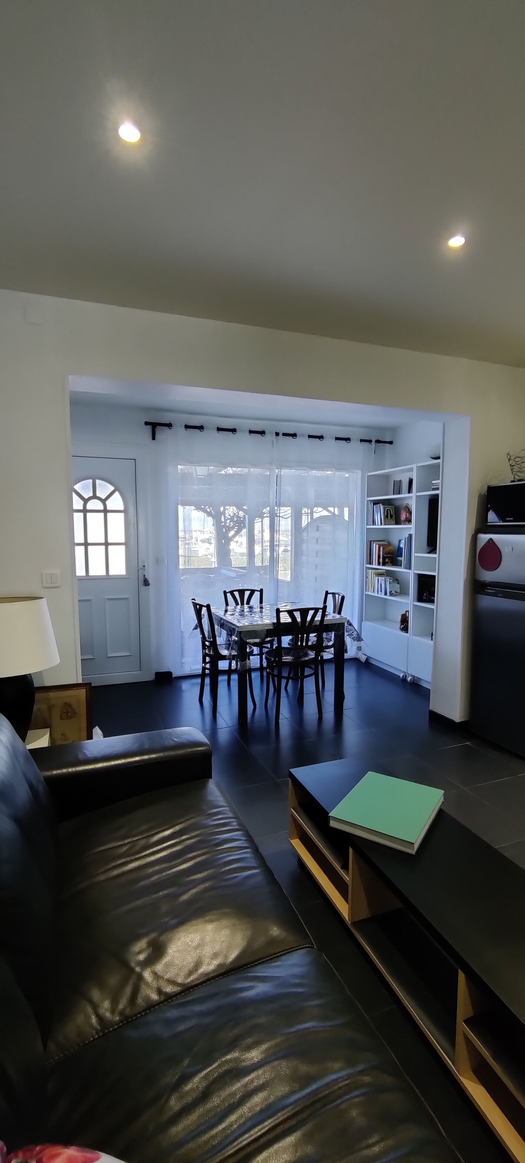 Een moderne woonkamer met een leren bank, een eettafel met stoelen en een keuken met een koelkast.