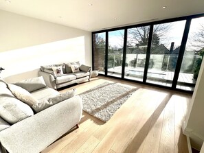 Relax in this spacious living room with a large sofa and balcony access.