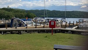 A marina with boats docked, a wooden pier, and a grassy area with a bench. - Stunning 3-bed Lodge in Windermere (Windermere)