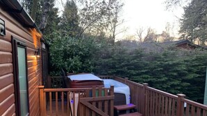A wooden deck with a hot tub, outdoor seating, and a staircase leading to a covered area. - Stunning 3-bed Lodge in Windermere (Windermere)